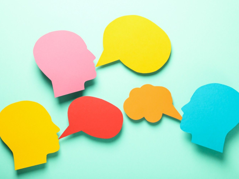 Ilustração de pessoas conversando com balões de fala coloridos, representando a escuta ativa de clientes nas pesquisas Win-Loss