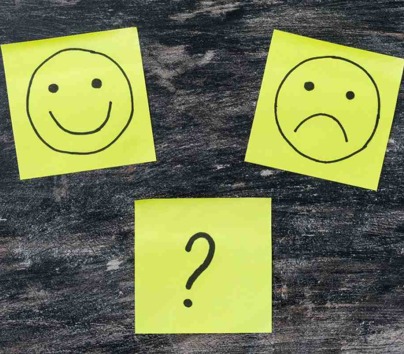 Três post-its amarelos com expressões de satisfação e dúvida, representando uma pesquisa NPS.